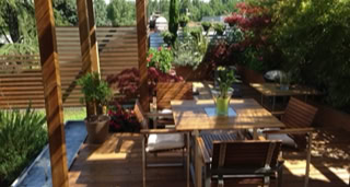 Terrasse und Pergola aus Holz mit Vegetation.