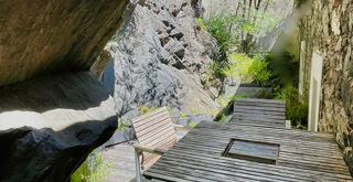 Terrasse extérieure entre le bâtiment et la montagne auquel l'édifice est adossé.