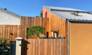 Tiny house urbaine à Vaulx-en-Velin. C'est une petite maison avec une façade et une clôture bois autour de son espace extérieur.