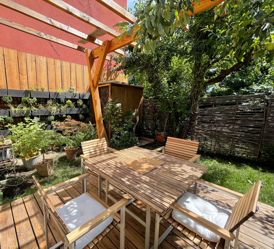 Terrasse extérieur avec pergola et entourée de végétation.