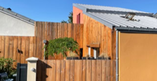 Façade bois de la tiny house, clôture bois autour de son espace extérieur.