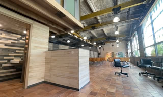 Tiers-lieu de la grunböx à Vienne. C'est une grande salle avec un carrelage qui rapelle la brique en façade et où les poutres jaunes utilisées lors des activités industrielles passées s'intègrent dans le décors.