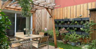 Outdoor space with a wooden terrace with pergolas and lots of vegetation.